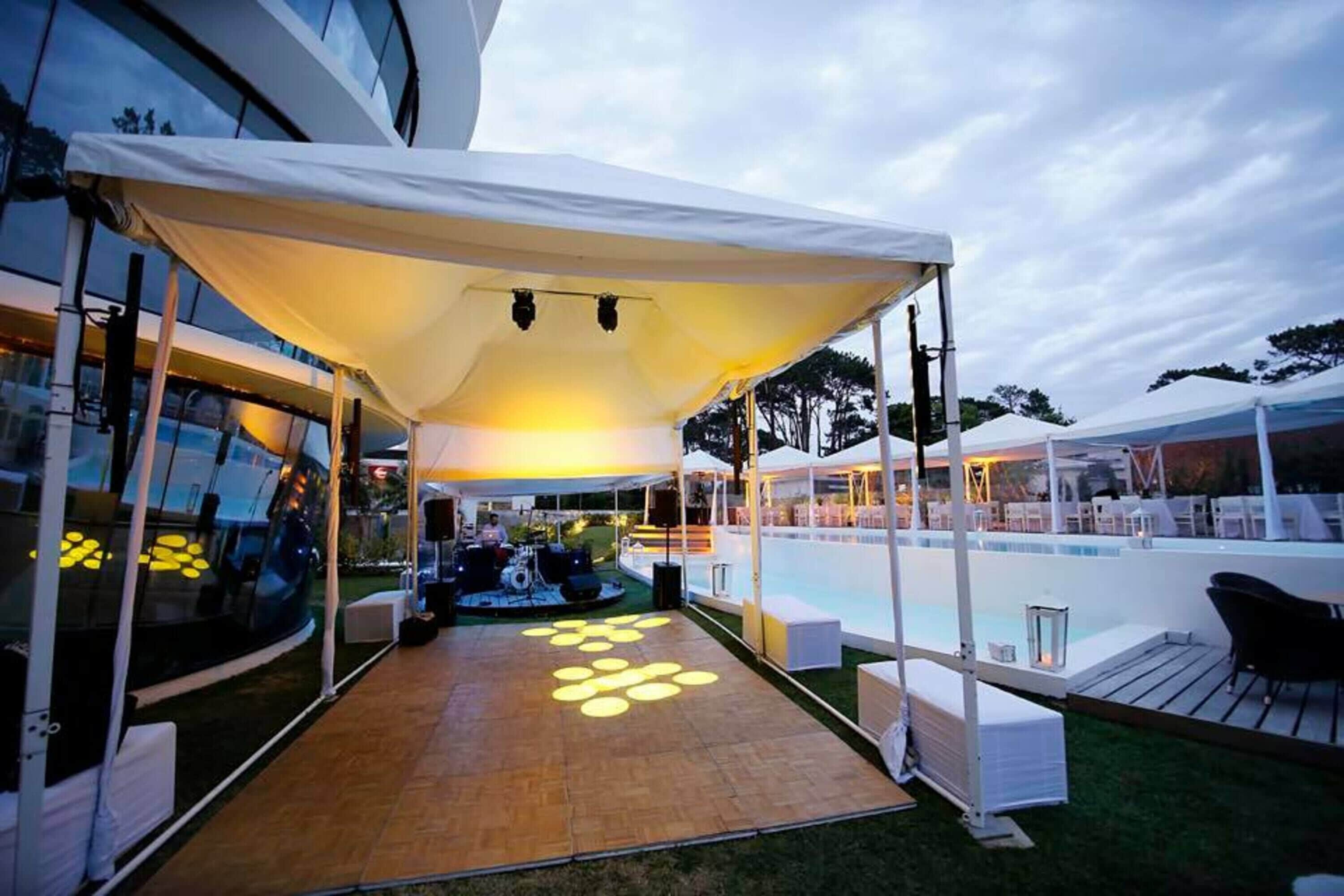 A covered outdoor area with a pool, seating, and a stage for entertainment.