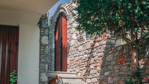 A stone building with a red door and a cat on the steps. - Casa Di Bella (Volos)