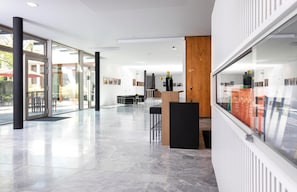 A modern interior with a glass wall, a reception desk, and a view of the outdoors. - Akademie Der Dioezese (Stuttgart)