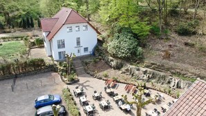 A white building with a red roof labeled 'Gästehaus' surrounded by a garden and outdoor seating area. - Hotel Restaurant Waldlust (Hagen)