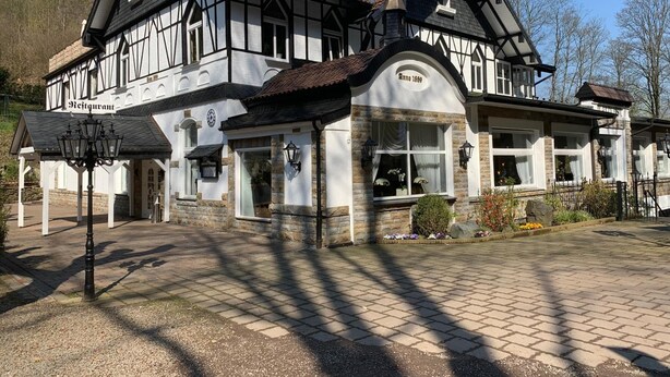 A traditional half-timbered building with a stone facade, multiple windows, and a central entrance.
