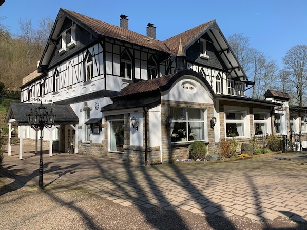 A traditional half-timbered building with a stone facade, multiple windows, and a central entrance.