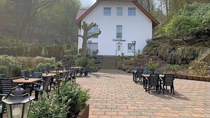 Un edificio con la leyenda 'Gästehaus', un patio empedrado y zona de estar al aire libre.