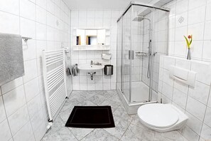 A bathroom with a white sink, mirror, toilet, and shower.