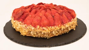 A round dessert with a patterned top, placed on a dark slate plate.
