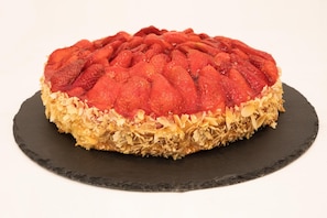 A round dessert with a patterned top, placed on a dark slate plate.