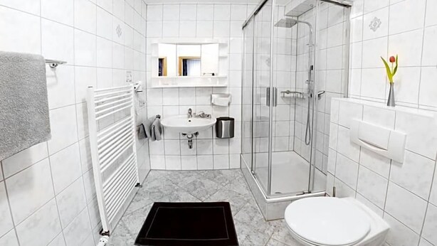 Un baño con lavamanos blanco, espejo, inodoro y ducha.
