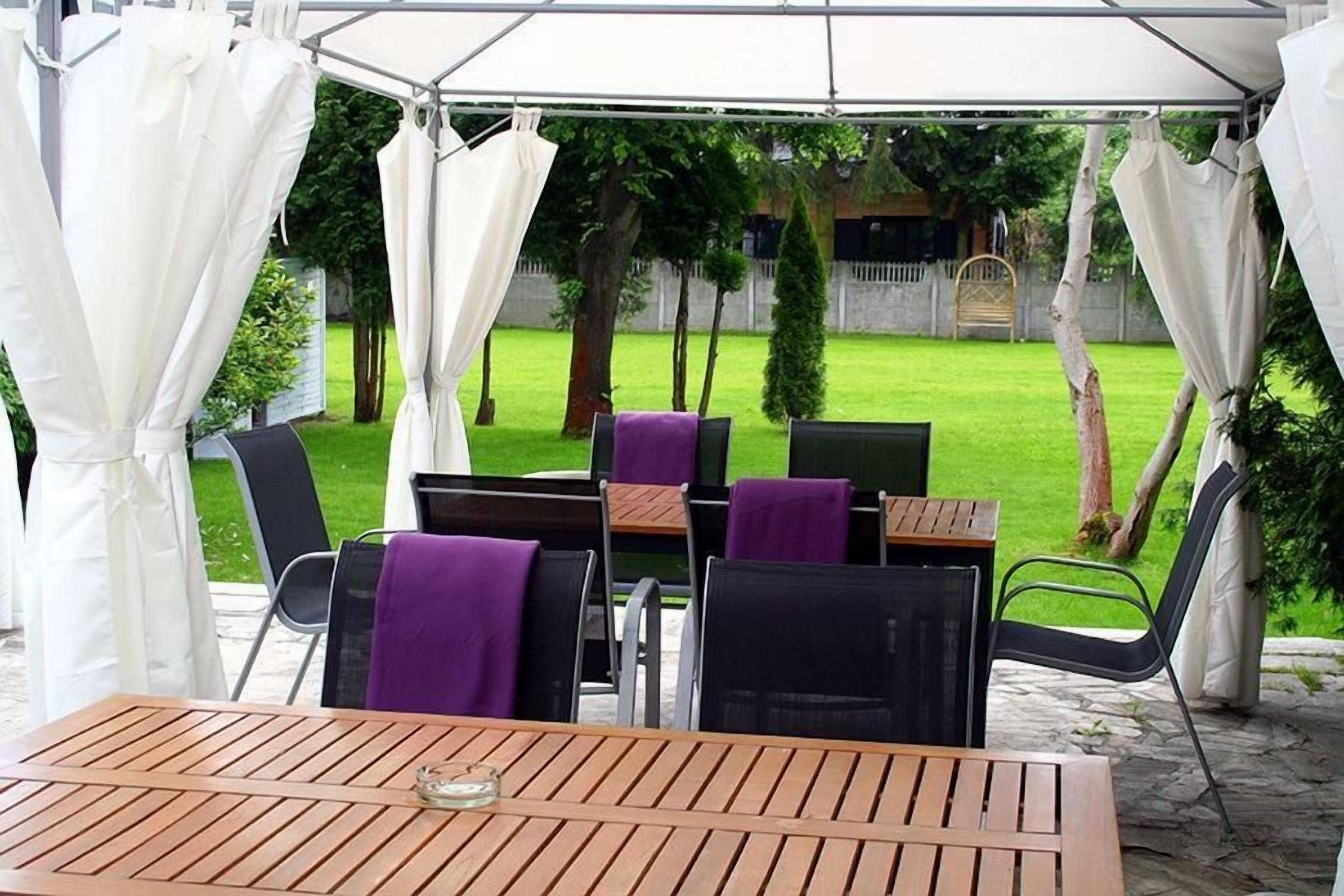 An outdoor patio area with a table and chairs, covered by a white canopy.