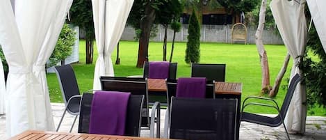 An outdoor patio area with a table and chairs, covered by a white canopy.
