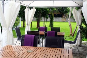 Un espace extérieur aménagé en terrasse, avec une table et des chaises, protégé par un auvent blanc.
