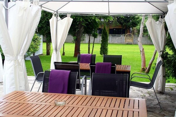 An outdoor patio area with a table and chairs, covered by a white canopy.