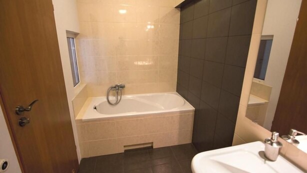 A bathroom with a bathtub, a sink, and a mirror.