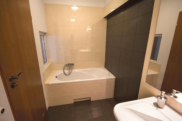 Une salle de bain avec une baignoire, un lavabo et un miroir.