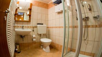 Un baño con ducha envuelta en vidrio, lavamanos e inodoro.