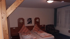 A bedroom with a wooden bed, two bedside lamps, a chair, and a window with blinds. - Desperados Hotel (Bergen)