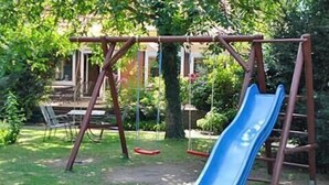 A playground with a blue slide, swings, and a picnic table. - Desperados Hotel (Bergen)