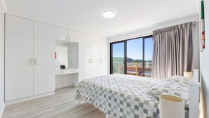 Une chambre avec un grand lit, une armoire, un bureau et une fenêtre donnant sur un beau paysage.