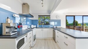 Une cuisine moderne dotée d’une grande fenêtre, d’une cuisinière, d’un four à micro-ondes et d’un évier.