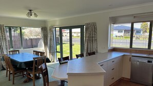 Una cocina amplia con una isla grande, un comedor con mesa y sillas, y vista al patio trasero a través de ventanas amplias.