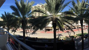 A view from a balcony overlooking a street with palm trees, a building with multiple floors, and a few people walking. - Miami Beach Luxury on South Beach Suite 303 (Miami Beach)