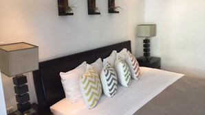 A neatly made bed with patterned pillows, a dark headboard, and two wall-mounted artworks above it. - Miami Beach Luxury on South Beach Suite 303 (Miami Beach)