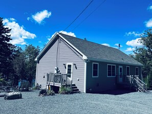 A single-story building with a gabled roof, a front porch, and a small staircase leading to the entrance. - Private Ocean Beach Front House (Hancock)