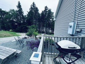 A deck with a grill, chairs, and a table. - Private Ocean Beach Front House (Hancock)