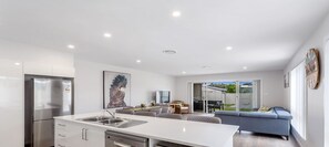 A modern kitchen with a built-in dishwasher, a stainless steel refrigerator, and an oven. - Pacific Paradise No.28 Anna Bay - New Home Close to Birubi Beach (ANNA BAY)