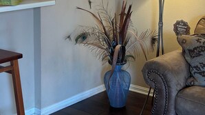 A living room with a decorative wall sign, a lamp, a blue vase, and a couch. - Luxury Condo on its Own Private Island on Lake Travis (Lago Vista)