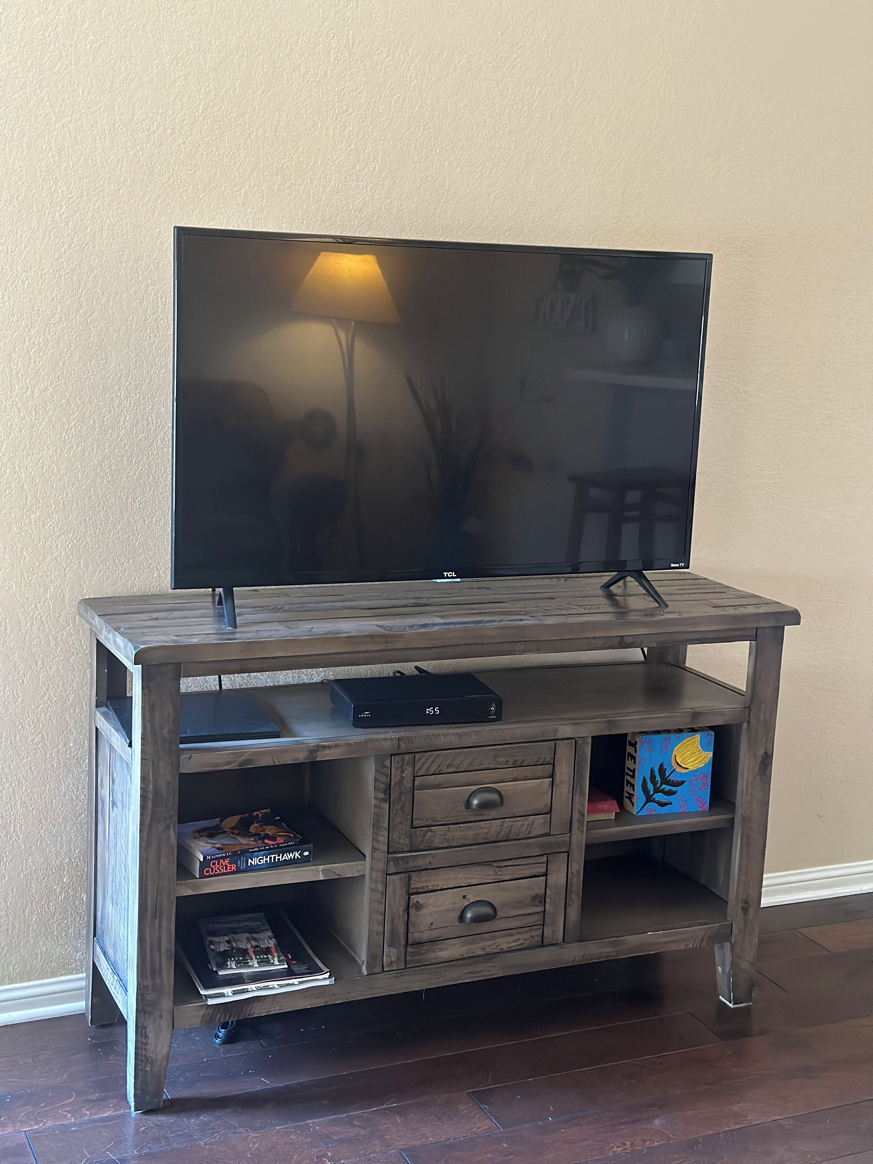 A wooden entertainment center with a flat-screen TV, shelves, and drawers.