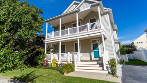 A two-story house with a front porch, a balcony on the second floor, and a blue door. - OCEAN BLOCK IN SOUTH REHOBOTH! (REHOBOTH BEACH)