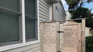 A wooden gate with two black handles, attached to a house with white siding and a window. - OCEAN BLOCK IN SOUTH REHOBOTH! (REHOBOTH BEACH)
