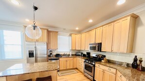 A modern kitchen with wooden cabinets, granite countertops, a stainless steel refrigerator, a microwave, an oven, and a coffee maker. - OCEAN BLOCK IN SOUTH REHOBOTH! (REHOBOTH BEACH)