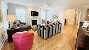 A living room with a fireplace, a television, and a ceiling fan. - OCEAN BLOCK IN SOUTH REHOBOTH! (REHOBOTH BEACH)