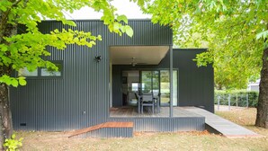 Une maison moderne dotée d’une grande porte vitrée donnant sur un espace de détente extérieur.