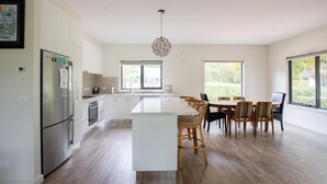 Une cuisine moderne dotée d’un îlot central, de meubles blancs et d’un coin repas avec des chaises en bois.