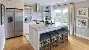 Una cocina moderna con una isla central, electrodomésticos de acero inoxidable y un amplio ventanal que proporciona luz natural.