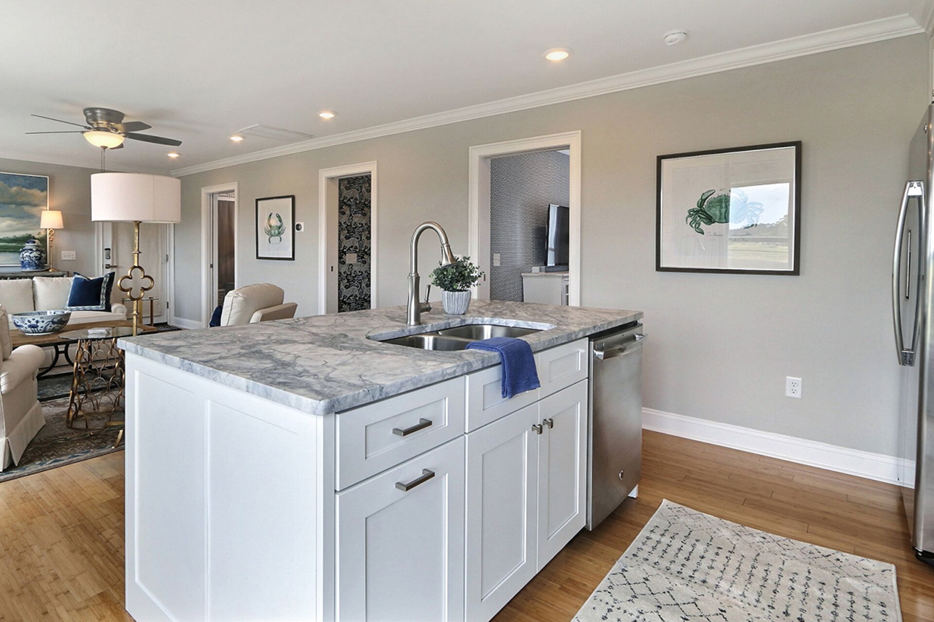 A modern kitchen with a marble countertop, white cabinetry, and a built-in dishwasher.