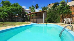 Una piscina con una escalera de metal, rodeada de césped y árboles.
