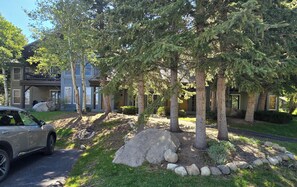 A residential area with a two-story house, a parked car, and a landscaped garden with trees and rocks. - Snowcreek Resort Vacation Rental 871 (Mammoth Lakes)