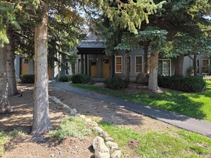 A building with a covered porch, a pathway leading to the entrance, and a well-maintained lawn. - Snowcreek Resort Vacation Rental 871 (Mammoth Lakes)