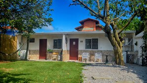 Ein zweistöckiges Haus mit rotem Dach, einer Veranda und einem kleinen Garten.