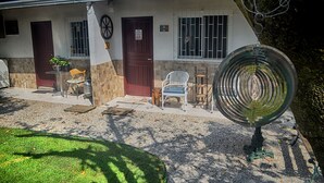 Ein Haus mit Veranda, einem kleinen Garten und einem Metallstuhl.