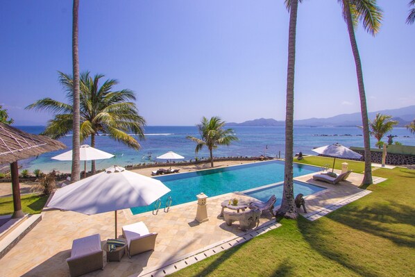 A pool area with lounge chairs, umbrellas, and a view of the ocean. - Three oceanfront luxury villas with sauna and tennis court (Sengkidu)