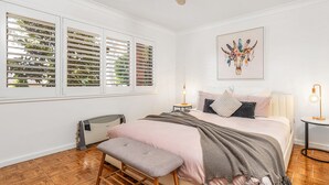 A bedroom with a bed, bench, bedside tables, and a radiator.