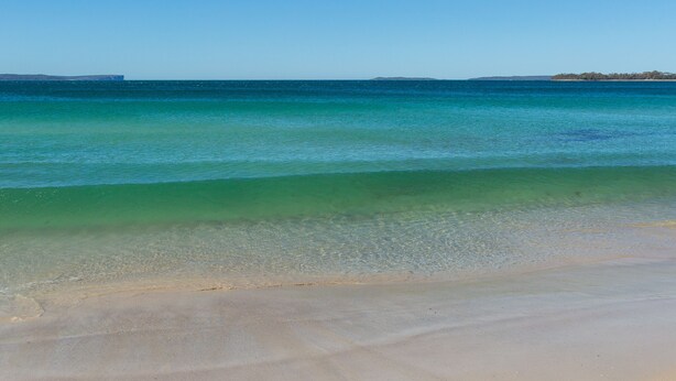 A beach with clear turquoise water and a sandy shore.