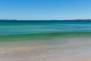 A beach with clear turquoise water and a sandy shore. - Southern Belle Jervis Bay. 2 minutes walk to Beach (Vincentia)