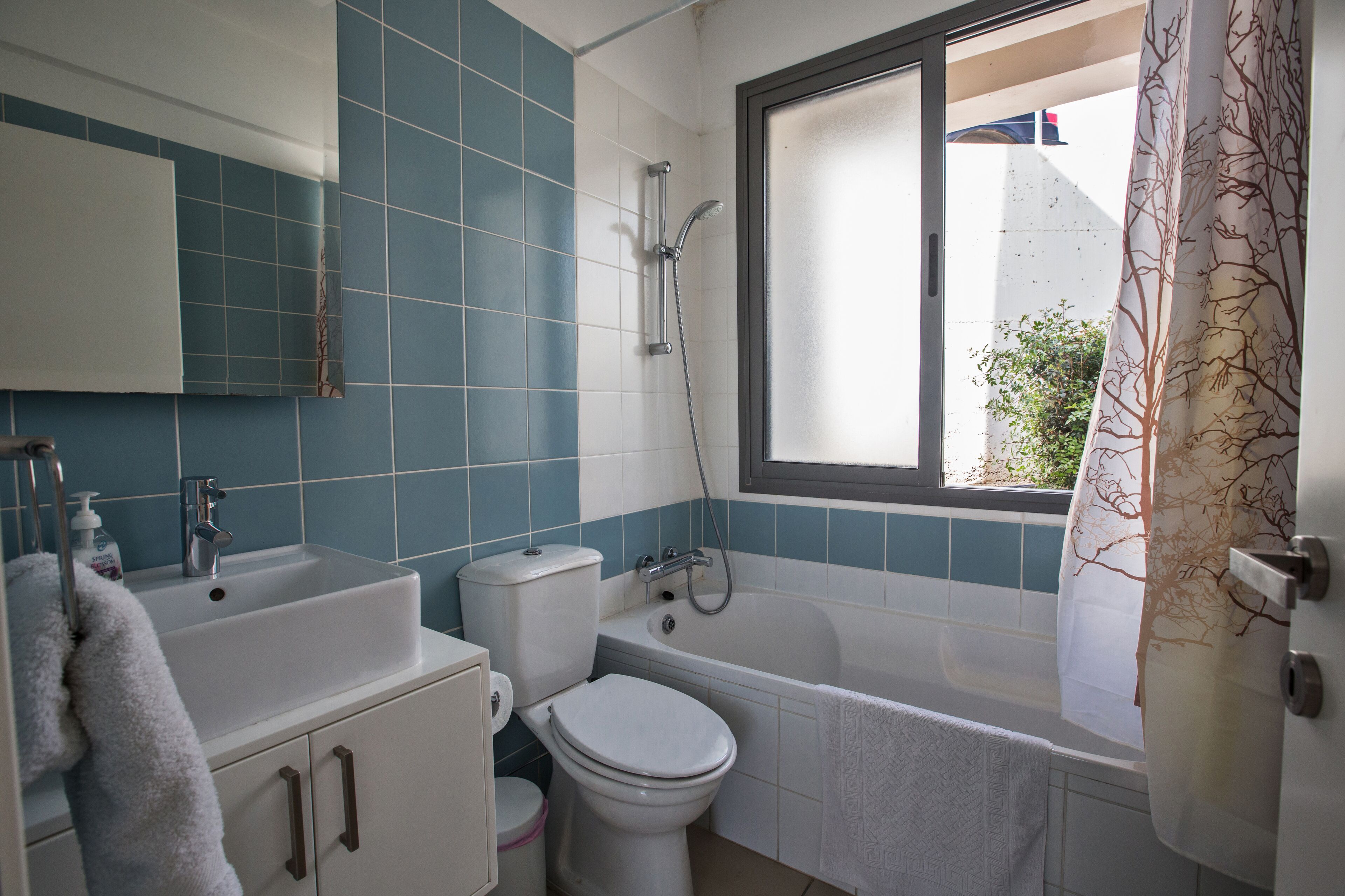 A bathroom with a bathtub, toilet, sink, and window.