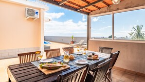 A dining area with a table set for four, outdoor chairs, a wooden ceiling, and a view of the ocean. - Funchal Bay View Villa by Madeira Sun Travel (Funchal)