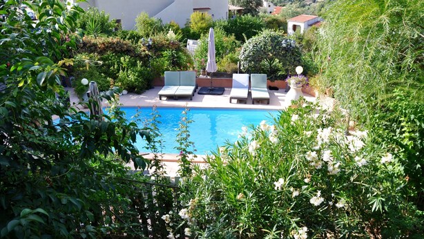 A pool area with lounge chairs and a pergola.